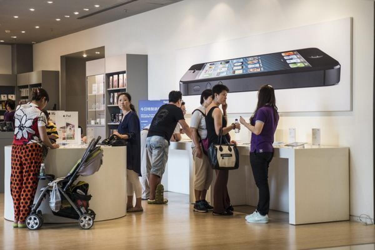 Customers at an Apple retailer in Beijing look at devices.