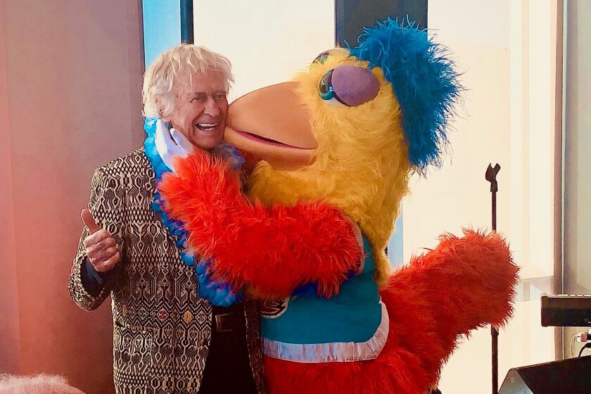 Dion Rich gets a hug and a peck on the cheek from The Famous Chicken during Rich's 90th birthday party Nov. 16 at a high-rise party space overlooking Petco Park.