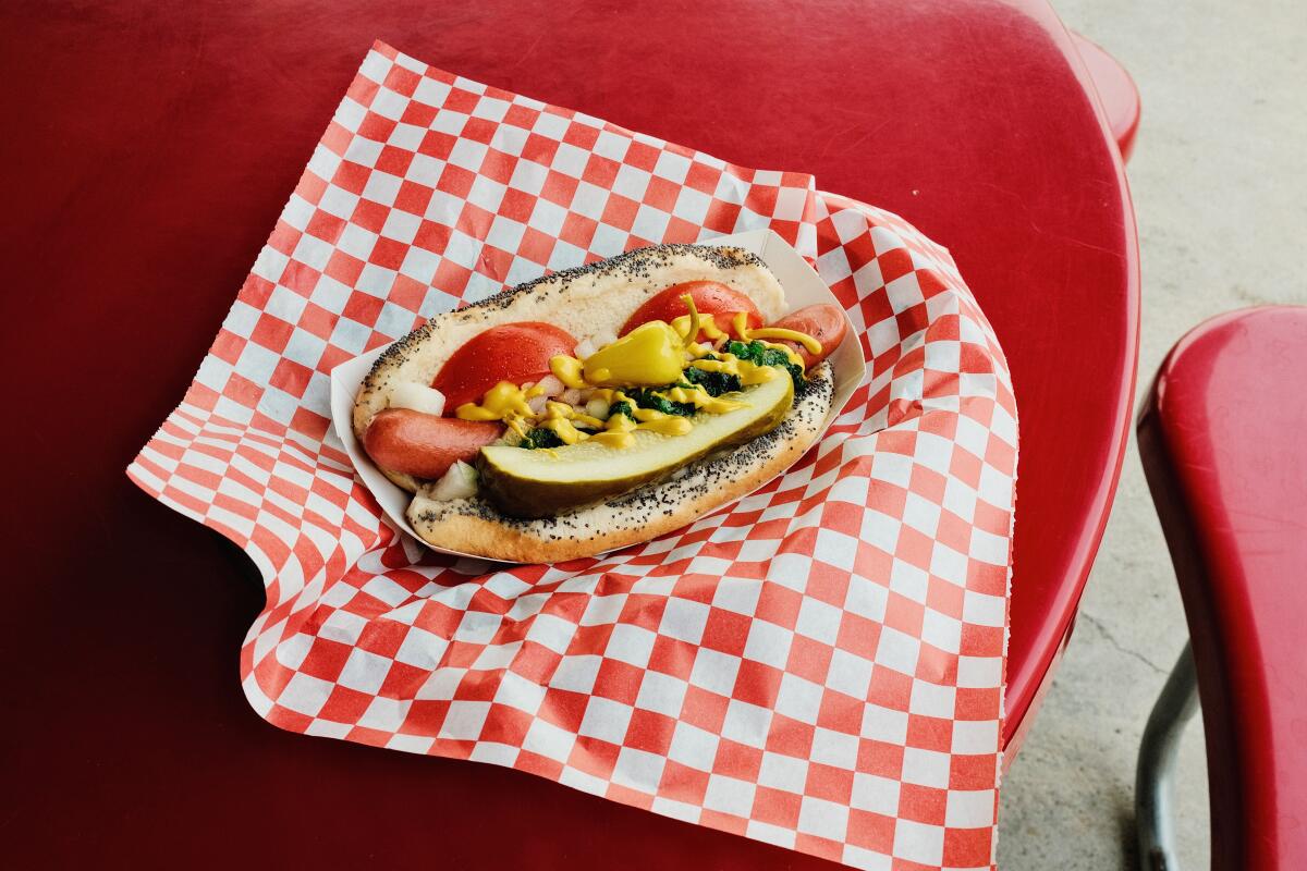A Chicago dog atop red-and-white-checkered paper on a red table at Larry's Chili Dog in Burbank.