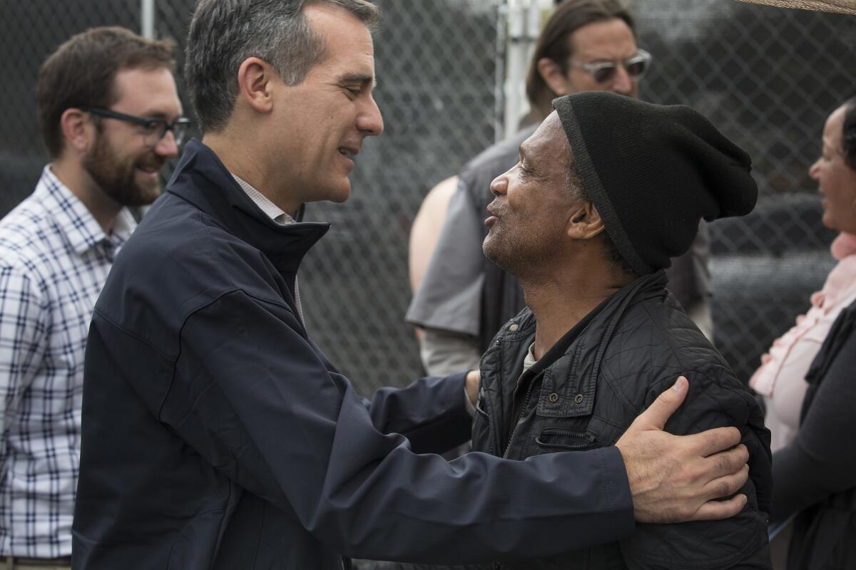 El alcalde de Los Ángeles, Eric Garcetti (izquierda) abraza Anthony Hereford, de 58 años de edad, en Hollywood durante una reunión con personas desamparadas.