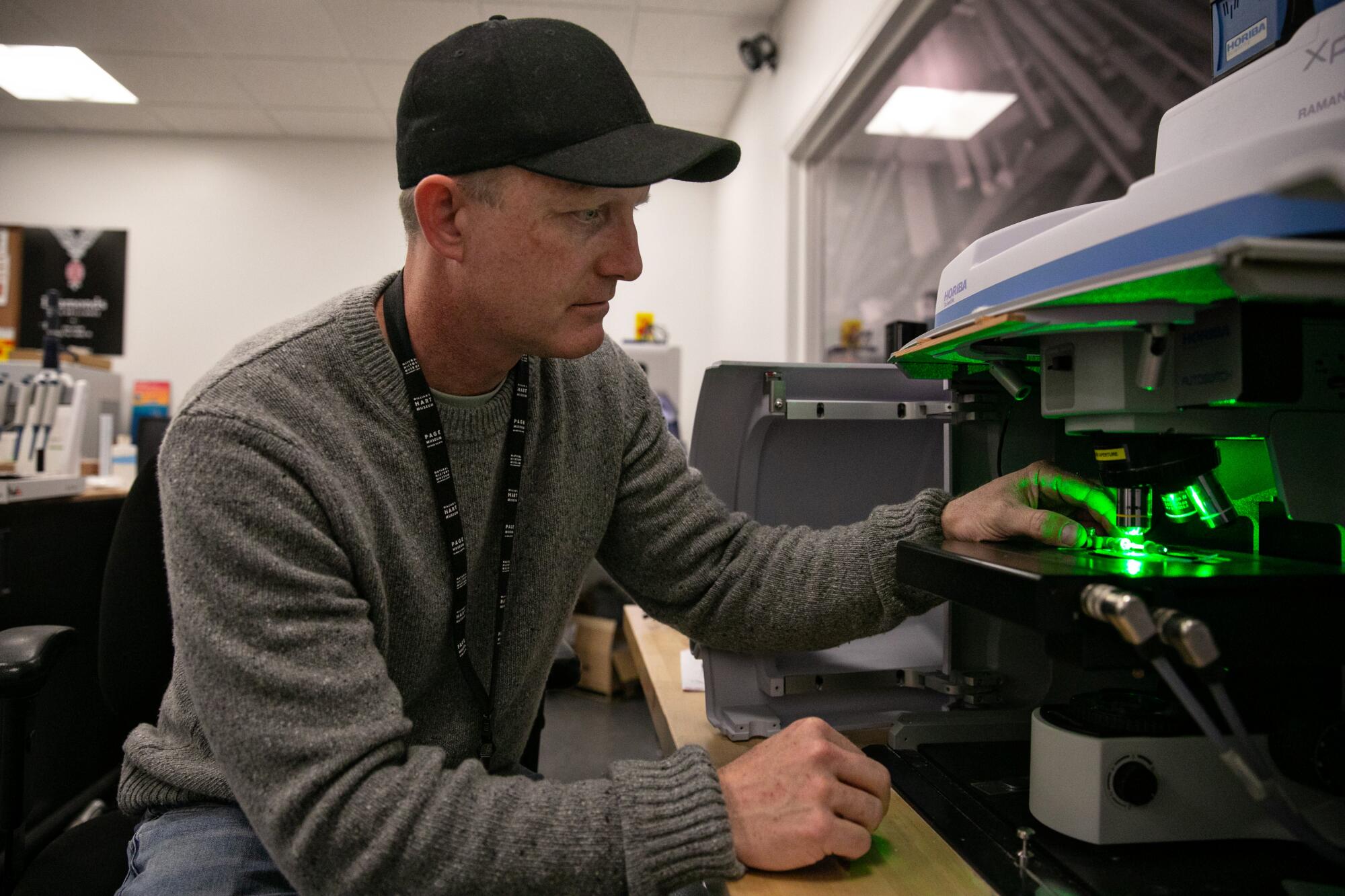 A man adjusts a slide on a microscope in a lab.