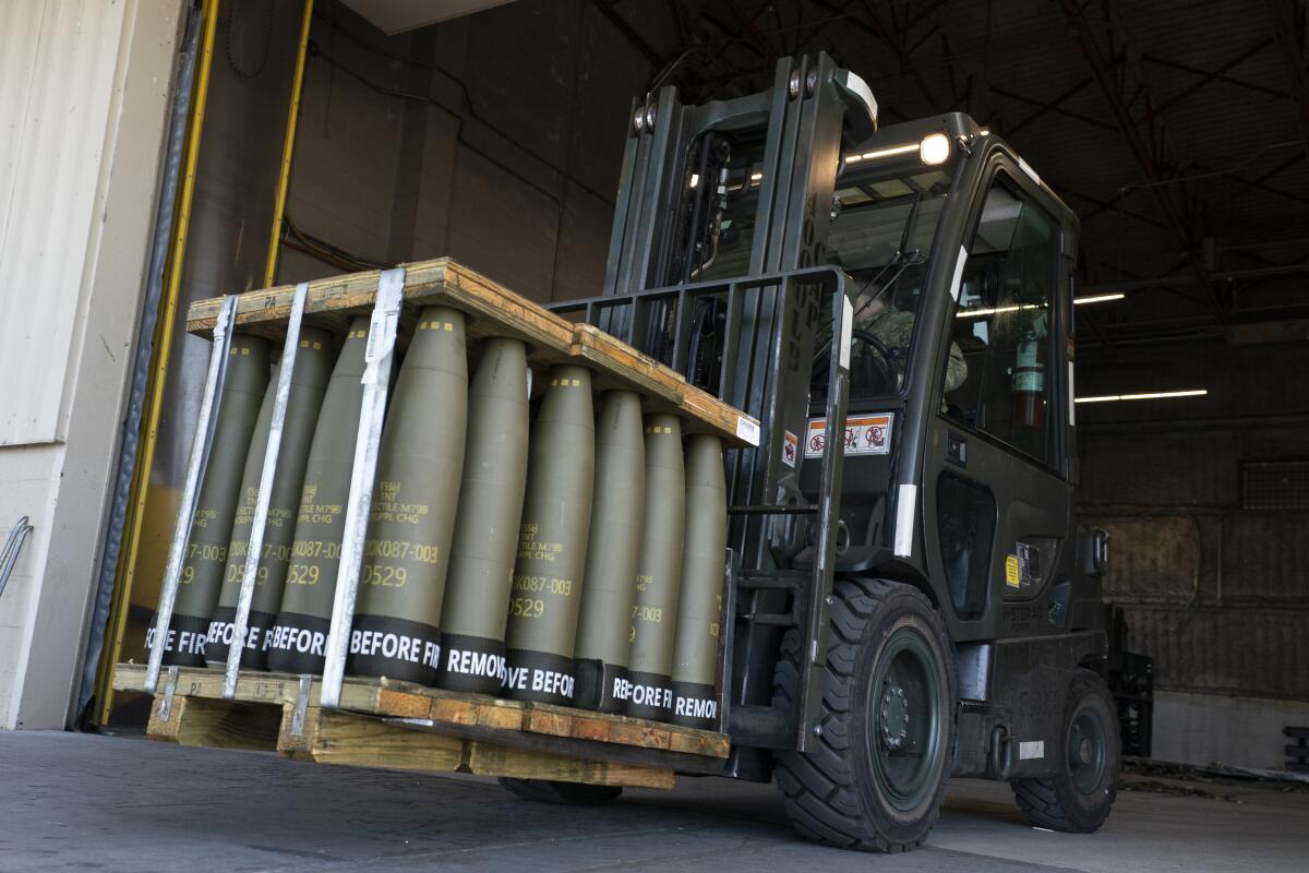 Airmen use a forklift to move 155-millimeter shells 