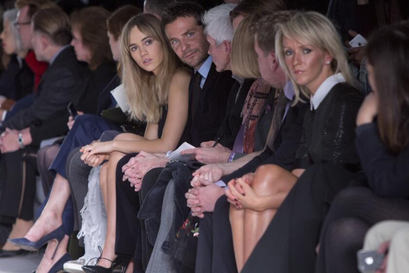 British model Suki Waterhouse, center left, sits next to her boyfriend Bradley Cooper as they watch Tom Ford's London Fashion Week show.