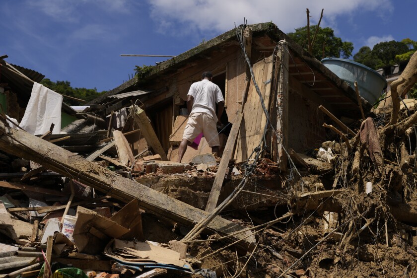 A resident stands on property destroyed by mudslides on the second day of rescue efforts in Petropolis, Brazil, Thursday, Feb. 17, 2022. Deadly floods and mudslides swept away homes and cars, but even as families prepared to bury their dead, it was unclear how many bodies remained trapped in the mud. (AP Photo/Silvia Izquierdo)