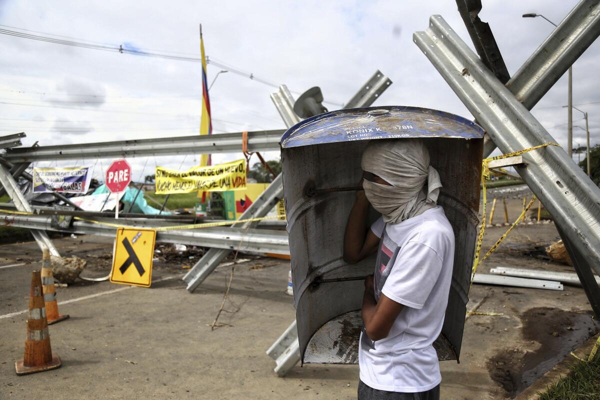 A protester stands at a road block set up during anti-government protests in Cali, Colombia, Monday, May 10, 2021. Colombians have protested across the country against a government they feel has long ignored their needs, allowed corruption to run rampant and is so out of touch that it proposed tax increases during the coronavirus pandemic. (AP Photo/Andres Gonzalez)