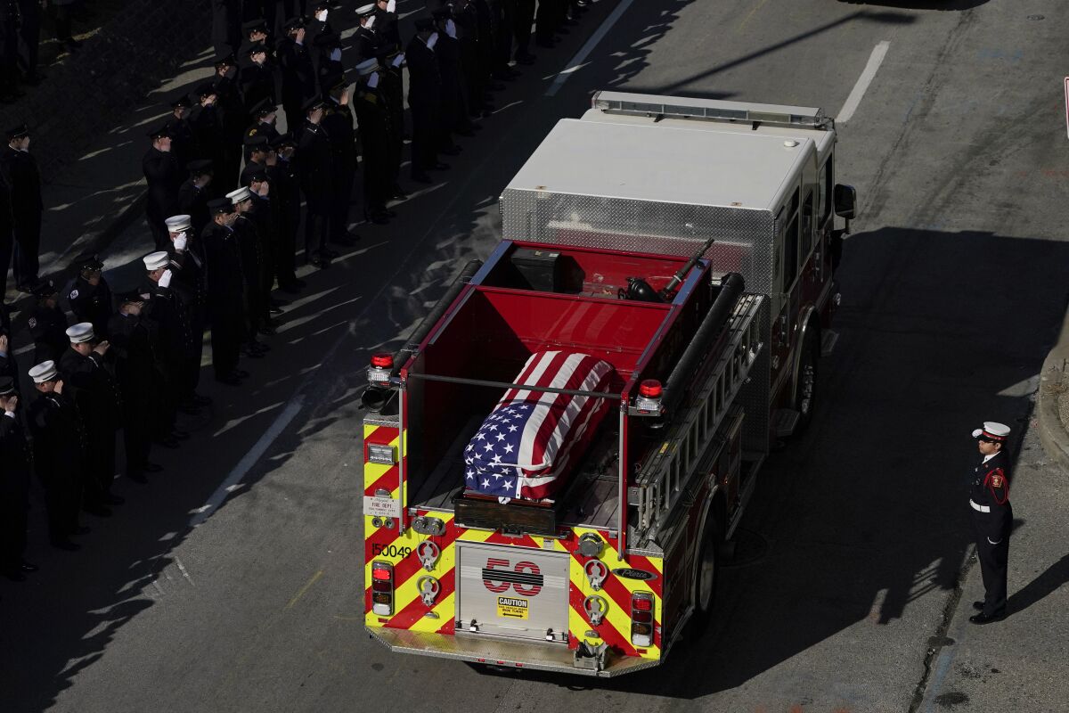 A fire engine carries the casket of Baltimore Fire EMT/firefighter Kenny Lacayo during a procession following a funeral service fo him, Lt. Paul Butrim and firefighter/paramedic Kelsey Sadler, Wednesday, Feb. 2, 2022, in Baltimore. The three fire officials died while responding to a vacant row home fire. A fourth firefighter was injured during the blaze. (AP Photo/Julio Cortez)