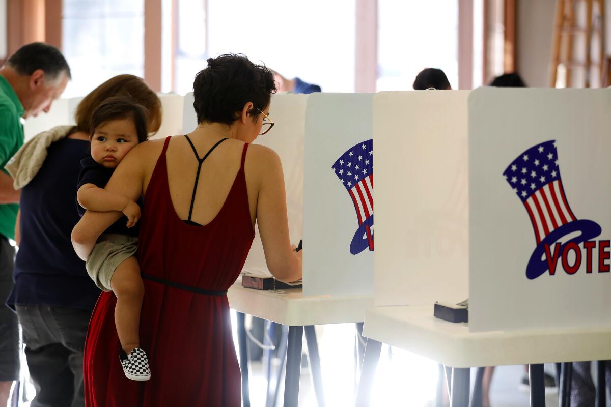 A voter holding a baby at a voting booth. 