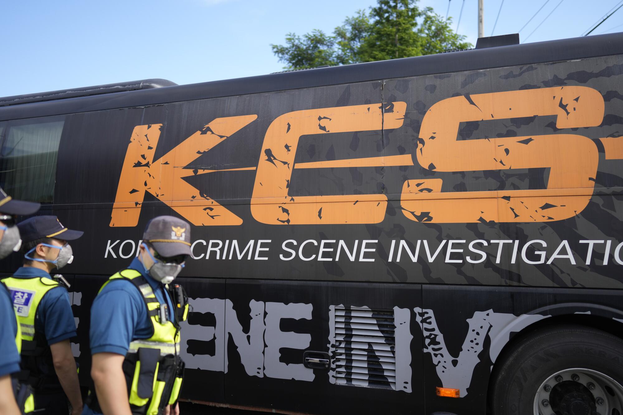 A vehicle marked "crime scene investigation" passes workers in yellow safety vests.
