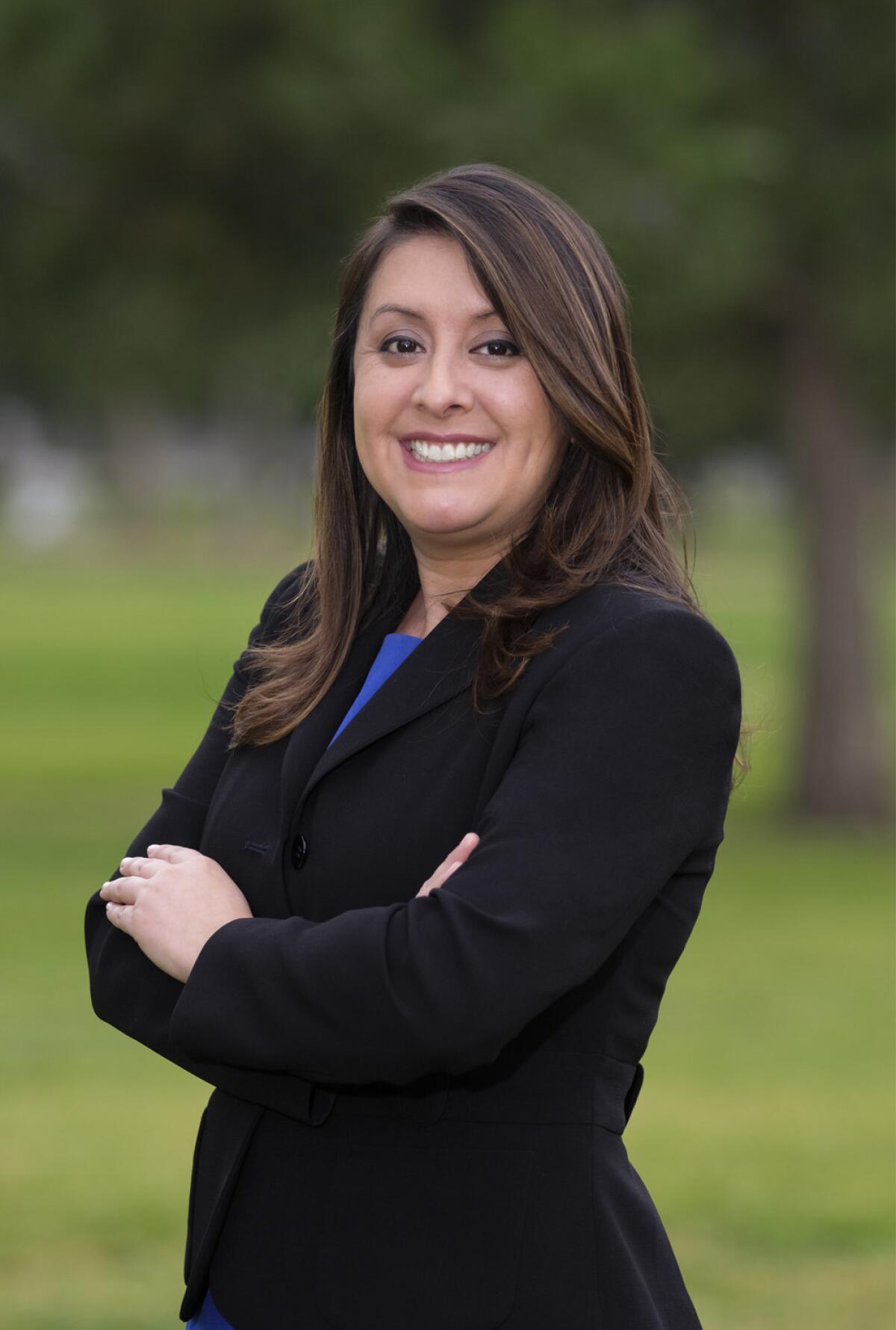 A woman wearing a dark jacket smiles.