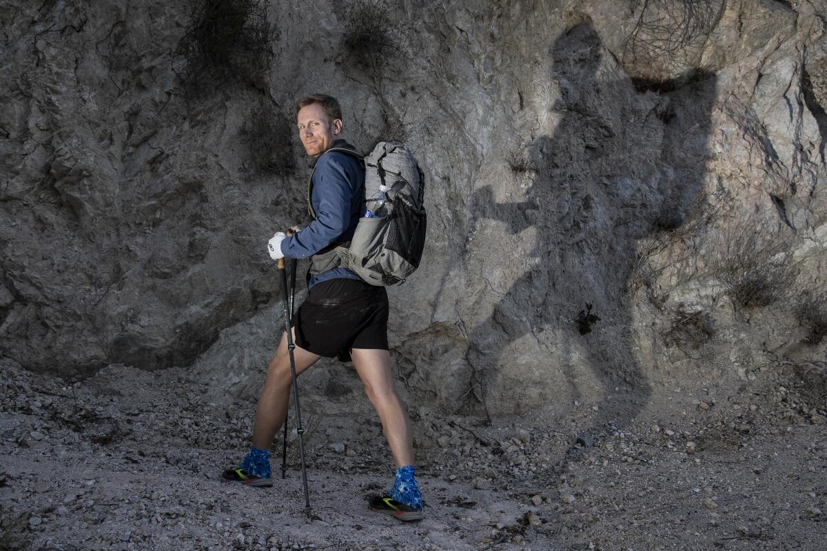 A hiker with a backpack stands on rocks near Angeles Crest Highway. 