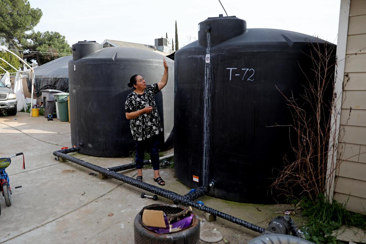 A woman stands next to a large water tank.