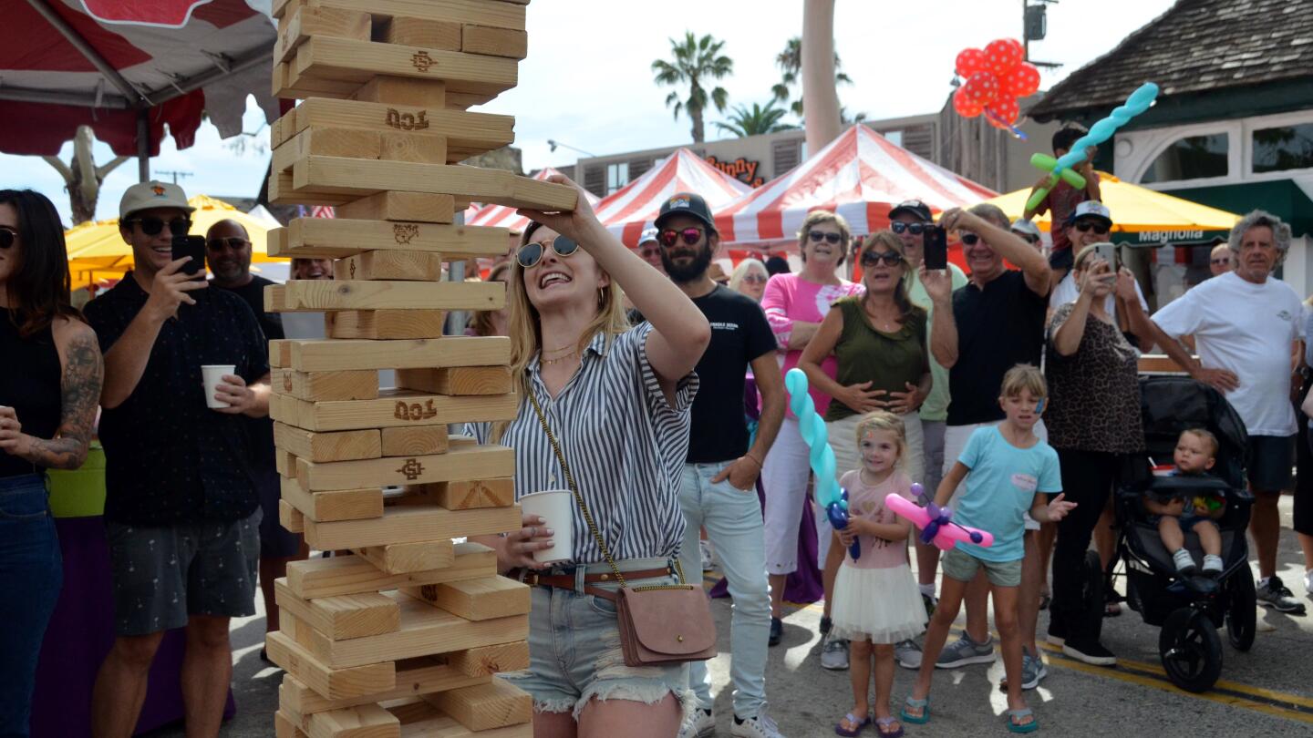 Kelly Knaggy carefully removes a block during a giant Jenga game Sunday during the Balboa Island Carnival & Taste of the Island.