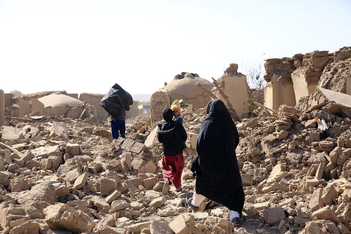 An Afghan woman with her children walk amid debris after a powerful earthquake.