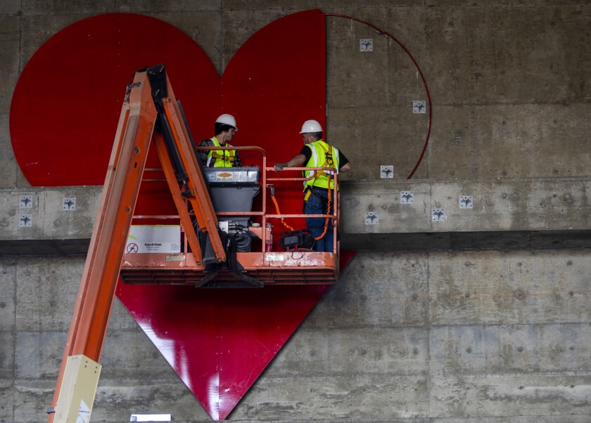 Construction workers install a giant heart at one end of the 3rd Street Tunnel.