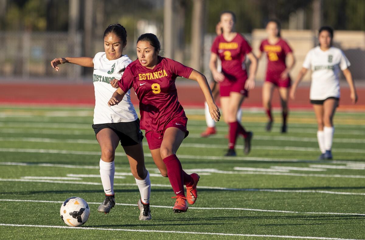 Costa Mesa's Jazmin Lopez (3) and Estancia's Desiree Mendoza (9) give chase to the ball during an Orange Coast League match on Thursday.