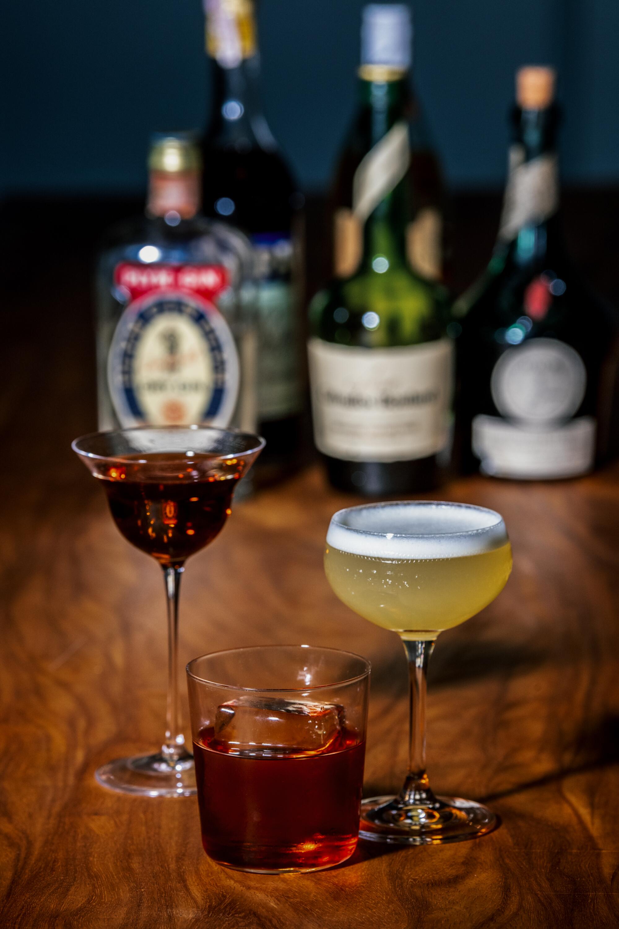 Three cocktails sit on a bar.