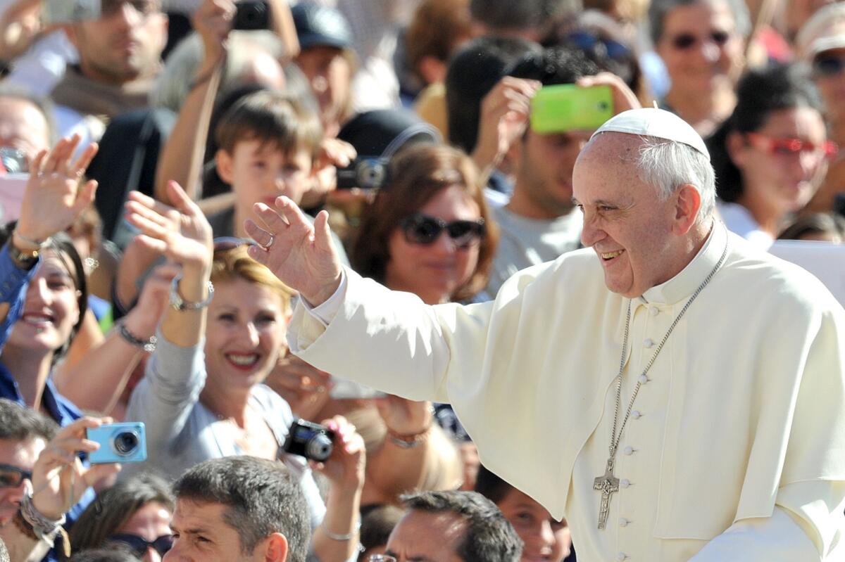 Pope Francis waves to the crowd as he arrives for a general audience in St. Peter's Square at the Vatican.