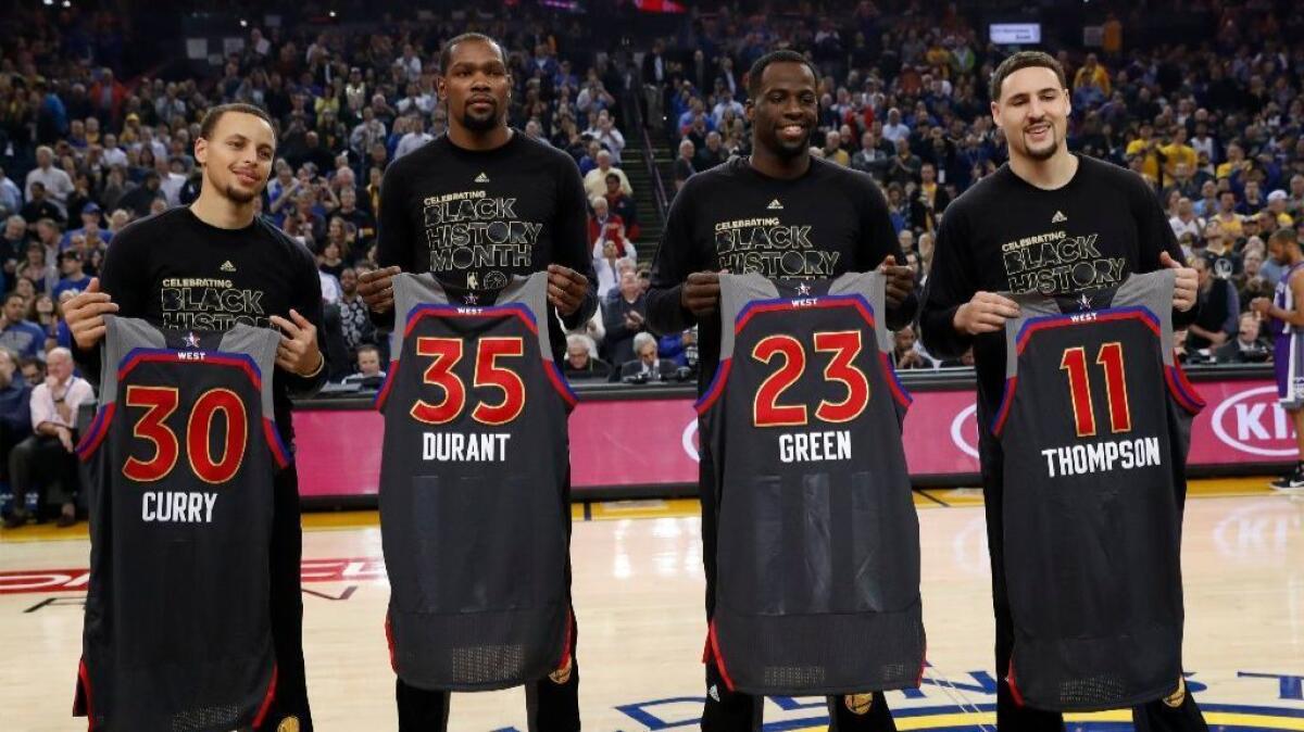 Golden State Warriors, from left to right, Stephen Curry, Kevin Durant, Draymond Green, and Klay Thompson hold up their NBA All-Star jersey's during a pre-game ceremony on Feb. 15.