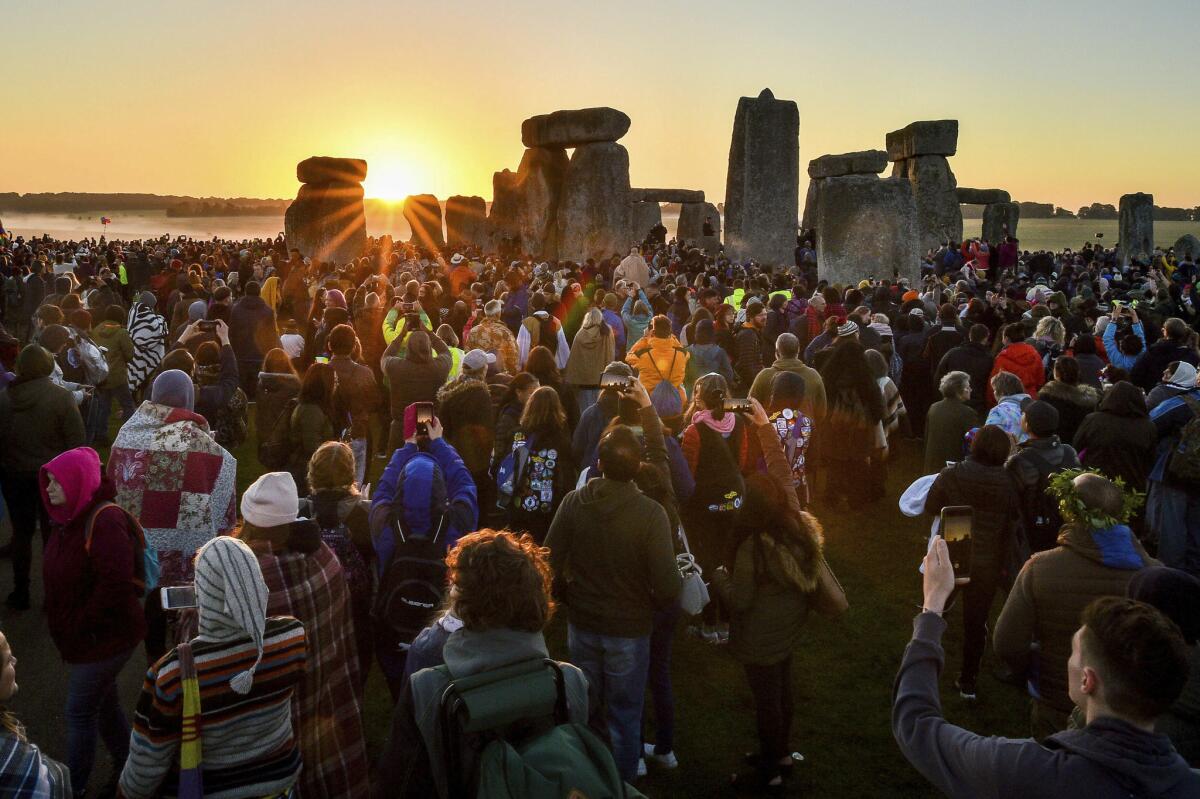 The sun rises between the stones at Stonehenge as crowds of people gather to celebrate the dawn of the longest day. (Ben Birchall / Associated Press)