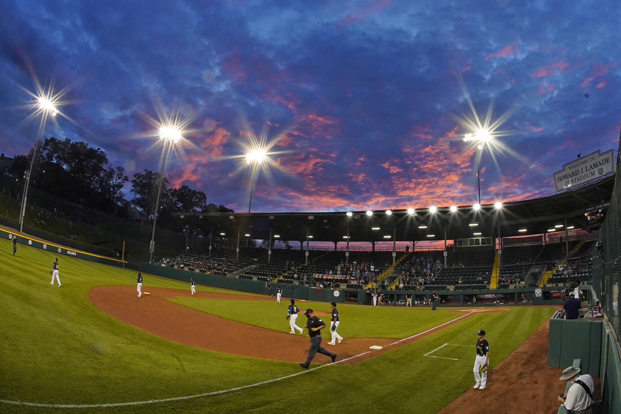 The sun sets behind Lamade Stadium during a baseball game