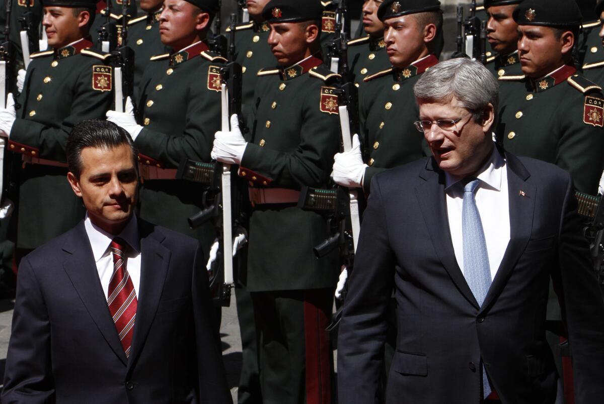 Mexico's President Enrique Peña Nieto, left, and Canada's Prime Minister Stephen Harper review the honor guard during a welcoming ceremony at the National Palace in Mexico City on Tuesday, a warm-up of sorts for Wednesday's one-day summit with President Obama.