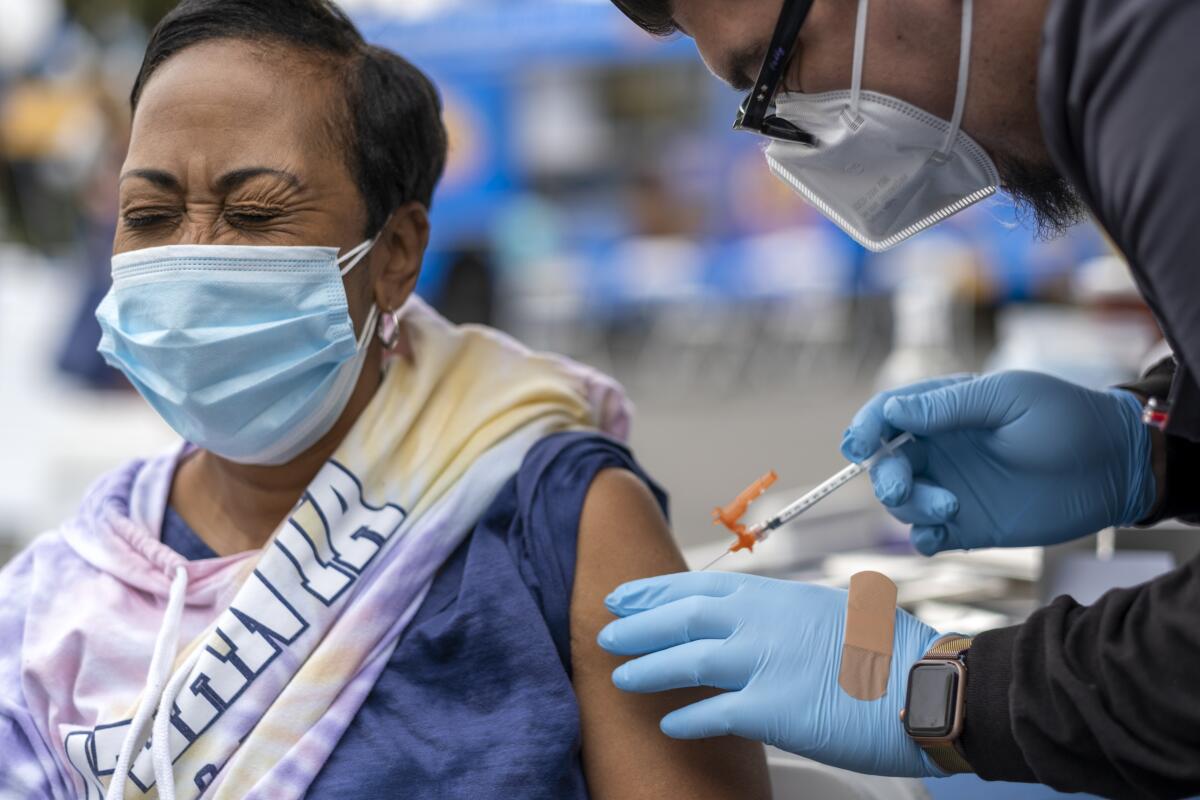 A woman winces while getting a shot.