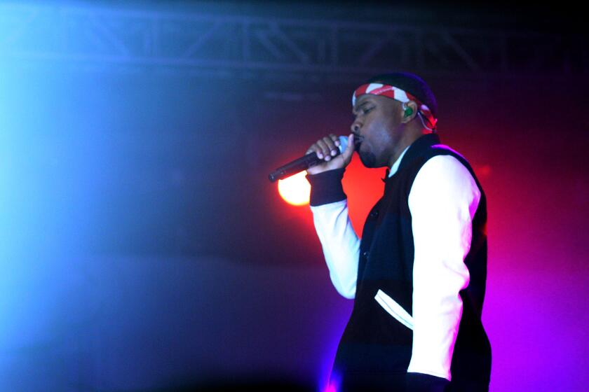 Frank Ocean sings into a microphone while wearing a jacket and a red headband