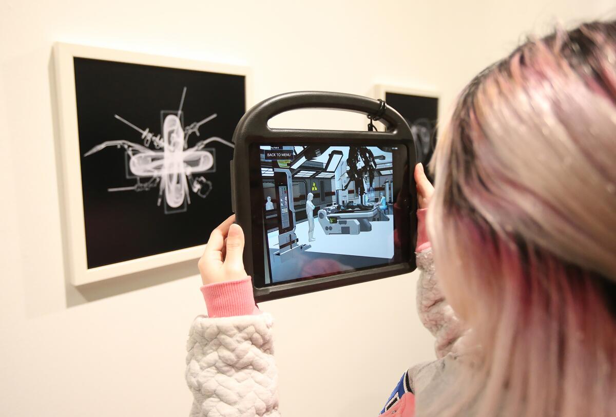 A guest peers into one of the augmented reality (AR) portals for a look into the vision of a post-Singularity world, during an exhibition of work by students in the new Immersive Media (VR/AR) program at OCC, now on display at the Frank M. Doyle Arts Pavilion.