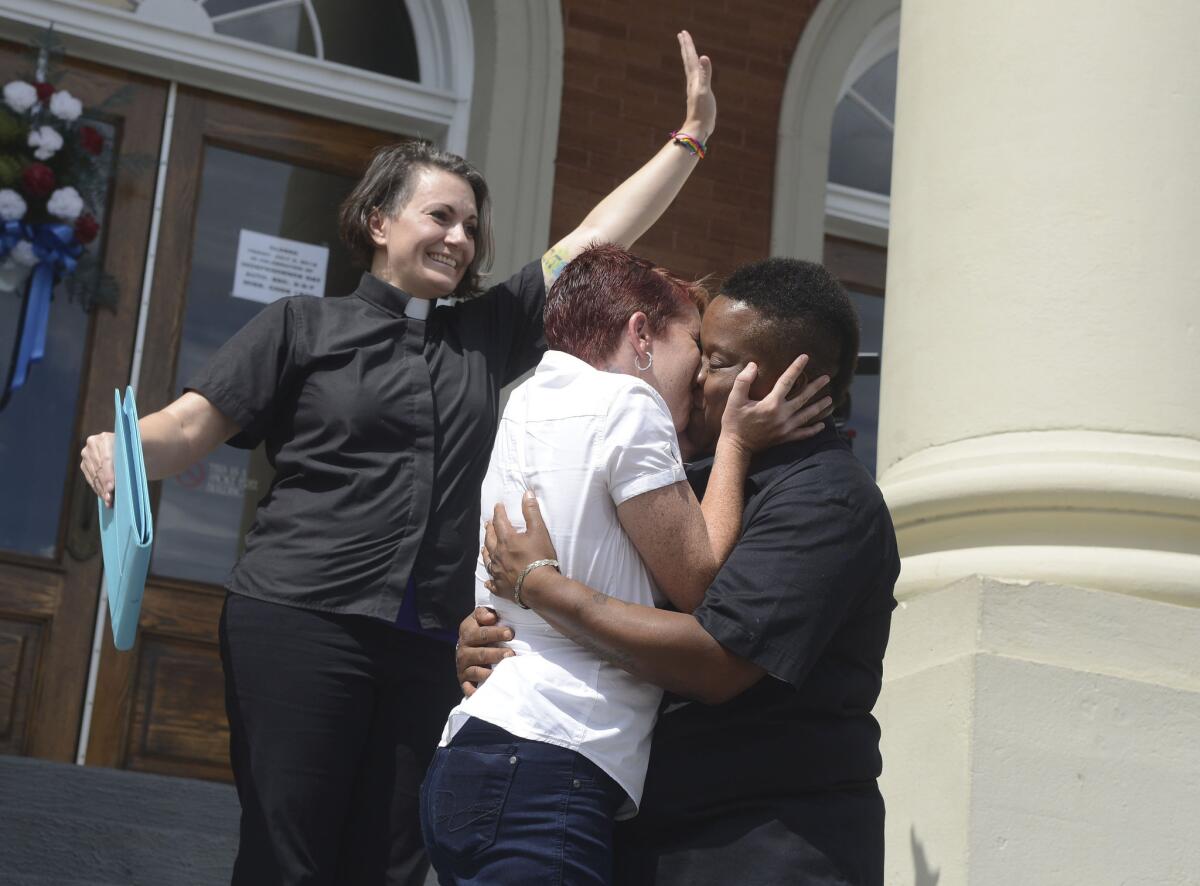 Amber Hamilton and Annice Smith share their first kiss as a married couple in front of by Pastor Brandiilyne Dear on the steps of the Forrest County Courthouse in Hattiesburg, Miss.