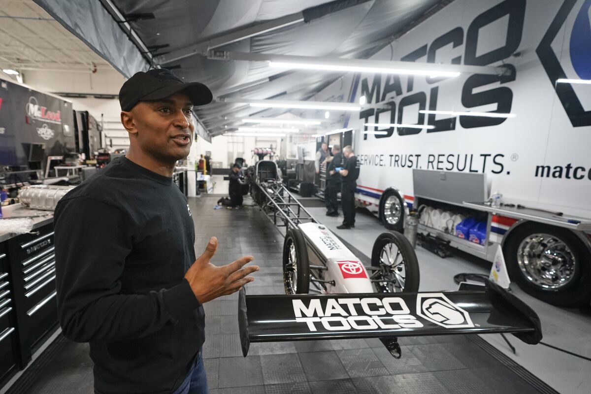 Antron Brown walks through the AB Motorsports Top Fuel team shop, Wednesday, Feb. 2, 2022, in Brownsburg, Ind. Antron Brown still walks into the same race shop he's called home for years. It's just different now. Sure, the 6,000-square foot area he rents still belongs to Don Schumacher Racing. And, yes, the banners hanging on the wall still reflect those three Top Fuel championships. But now the 45-year-old Brown finds himself digging through papers and boxes, waiting for deliveries and calling the shots as a new NHRA season beckons. This is Antron Brown's new life — as an owner-driver.(AP Photo/Darron Cummings)
