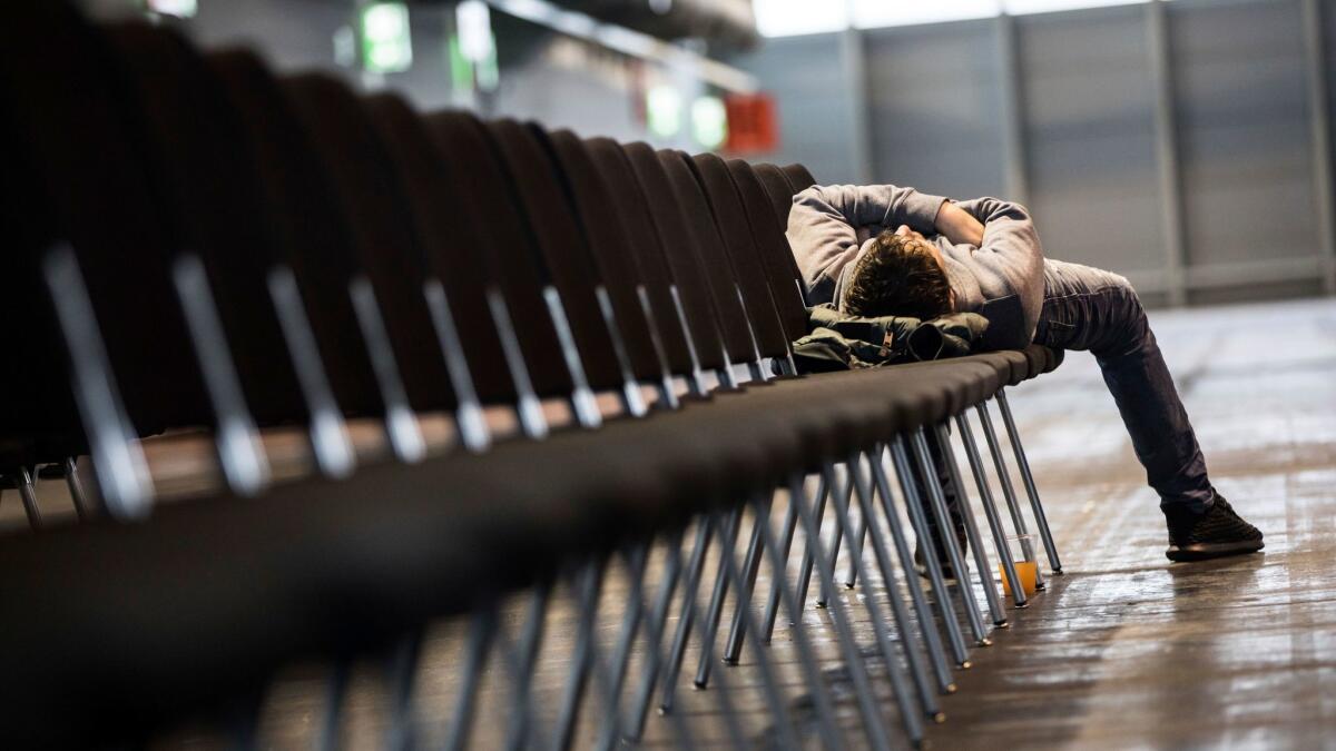 A man sleeps in a fairgrounds hall during the evacuation of 65,000 people in Frankfurt, Germany.