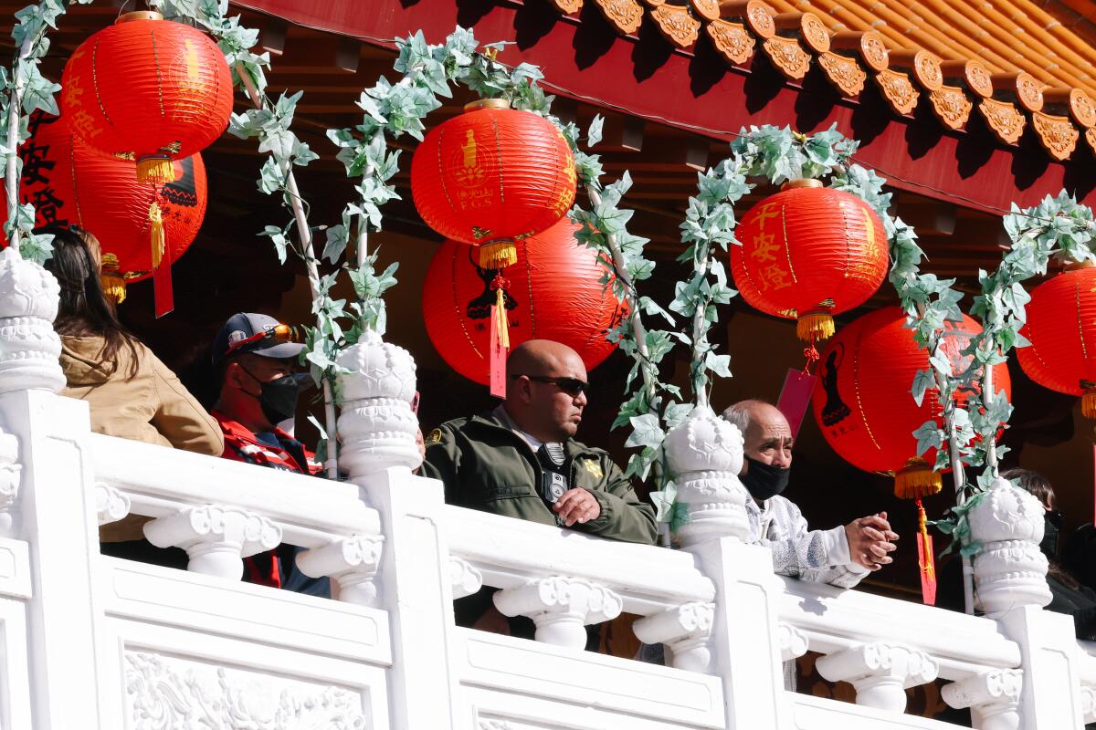 A sheriff's deputy stands with others along a balcony railing during a Lunar New Year celebration