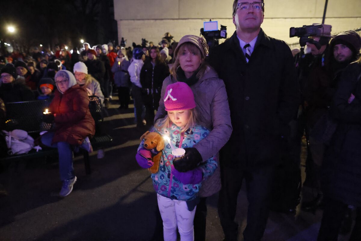 A small child takes part in a candlelight vigil in downtown Waukesha, Wis.
