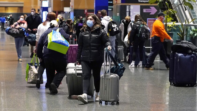 Travelers lug their bags while walking through a terminal at Boston's Logan Airport on Tuesday.