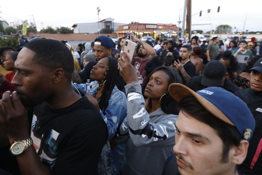 LOS ANGELES, CA - MARCH 31, 2019 - - A crowd of people look over the scene where rapper Nipsey Hussle was killed in a shooting outside his store and left two others wounded in South Los Angeles on March 31, 2019. (Genaro Molina/Los Angeles Times)