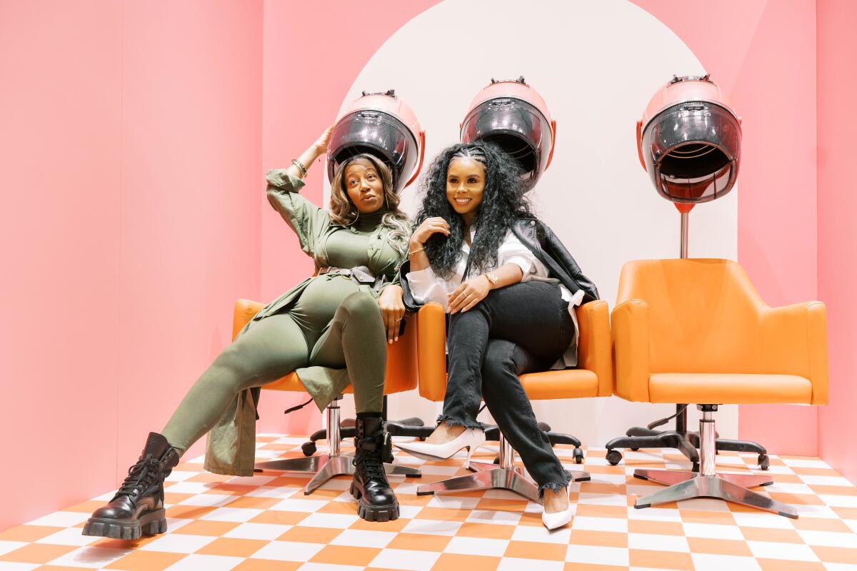 Two women pose in a hair-drying installation.