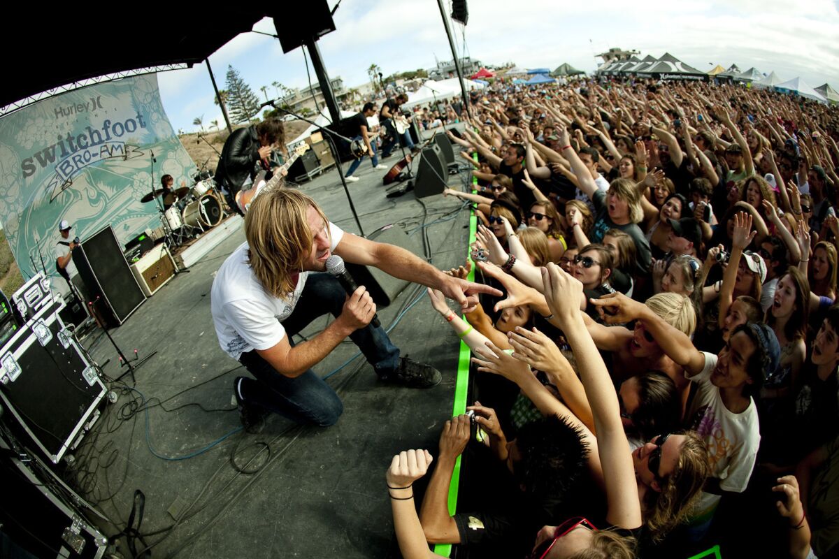 Jon Foreman (shown crouching) and Switchfoot have been holding their Bro-Am concert and surf contest at Moonlight Beach in Encinitas since 2005. The 2020 edition will take place online because of the coronavirus pandemic. 