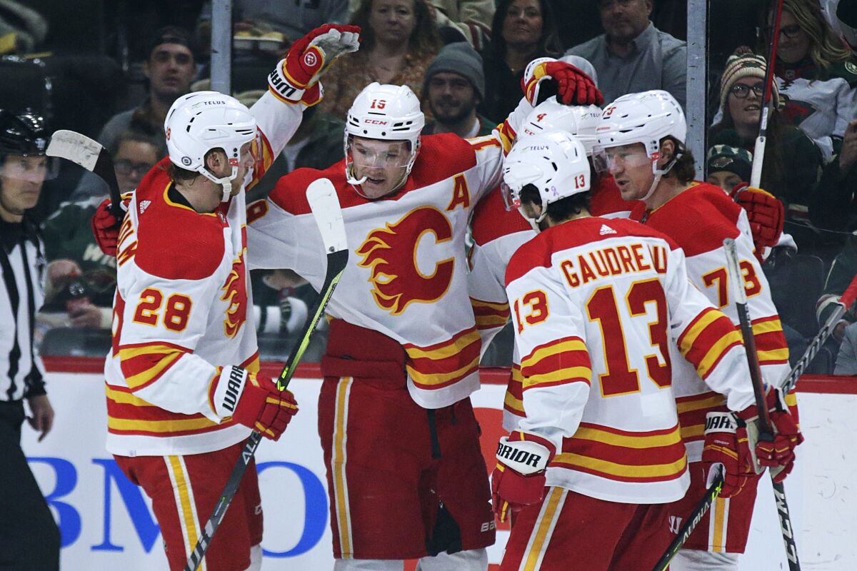 Calgary Flames left wing Matthew Tkachuk (15) celebrates his goal against the Minnesota Wild with teammates Elias Lindholm (28), Rasmus Andersson (4), Tyler Toffoli (73) and Johnny Gaudreau (13) during the first period of an NHL hockey game Tuesday, March 1, 2022, in St. Paul, Minn. (AP Photo/Andy Clayton-King)