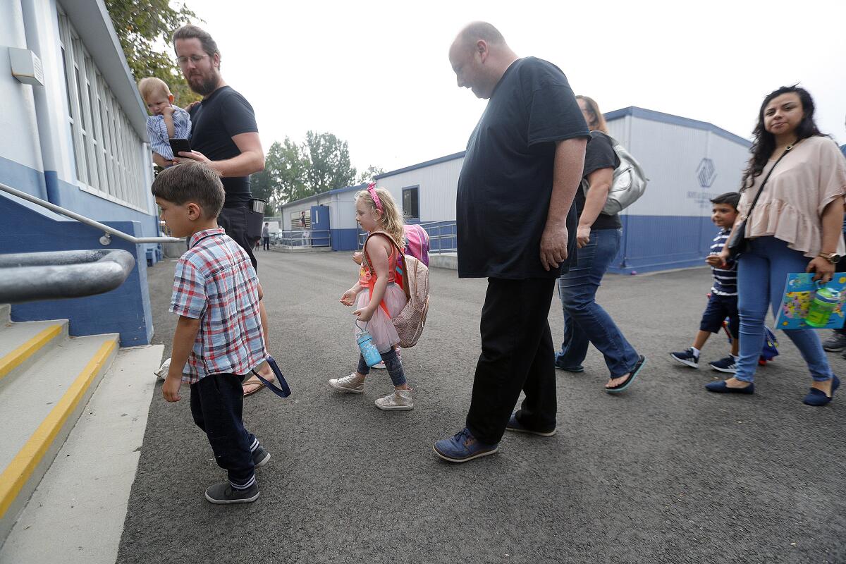 Kindergarten parents and children walk on campus on the first day of school at Bret Harte Elementary on Aug. 12. While a quality education may be considered priceless, Burbank Unified estimates it loses $51 in state funding every time a student is absent.