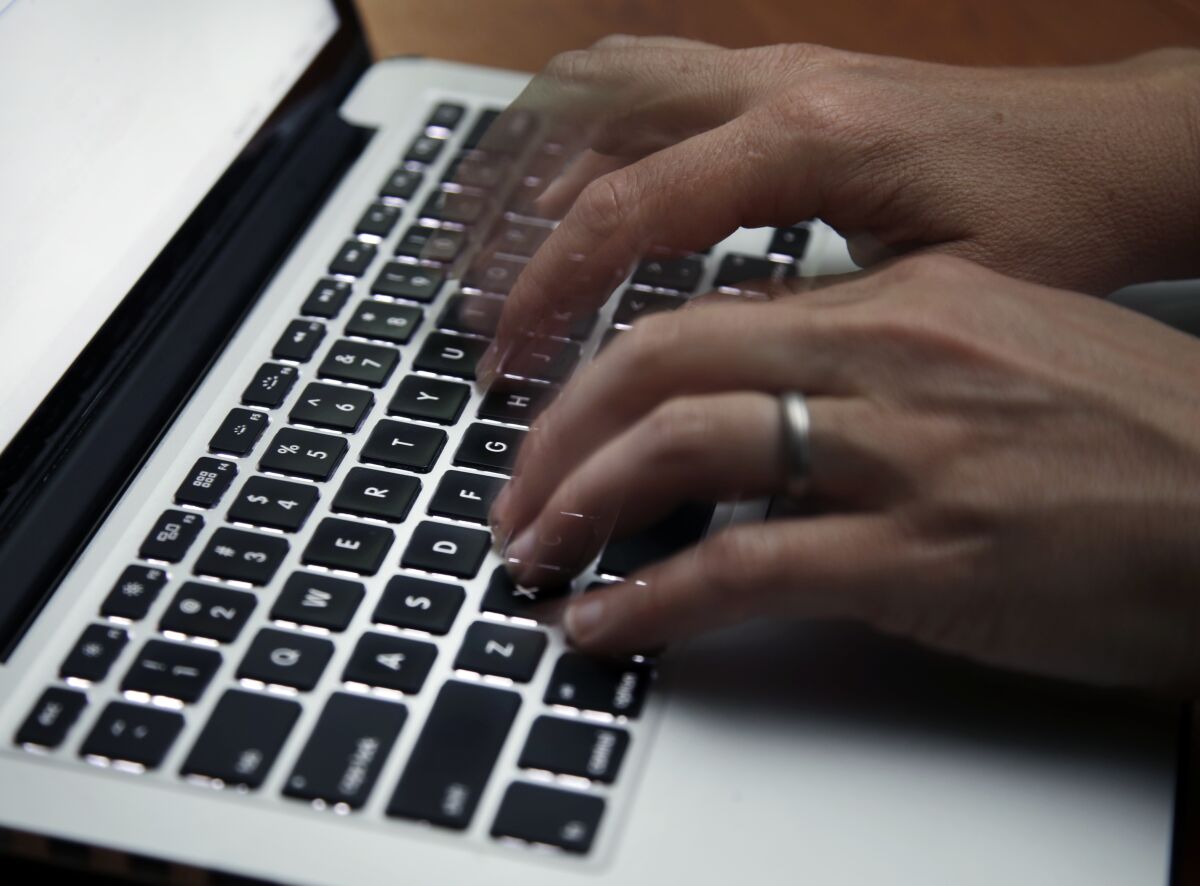 Two hands typing on a laptop