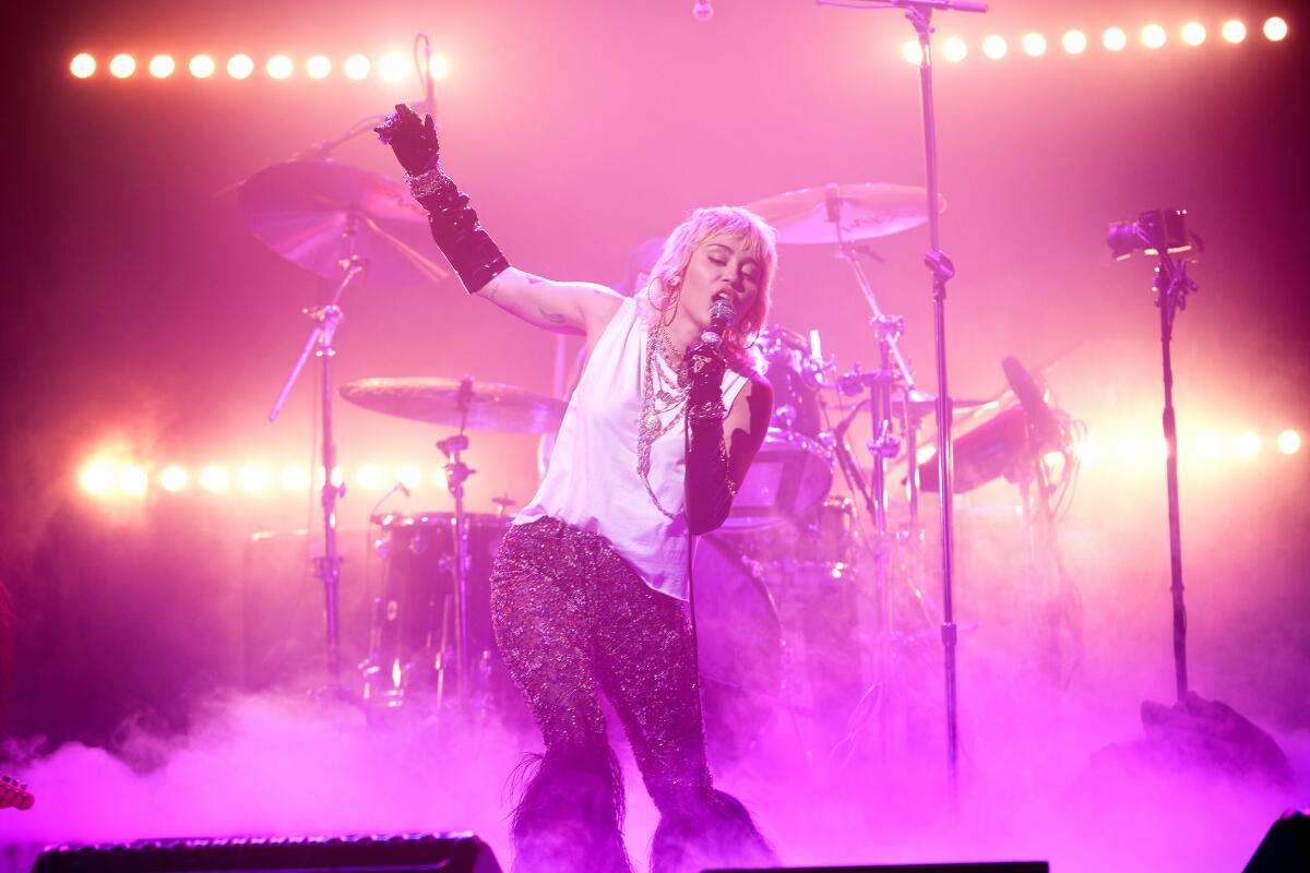 A female singer on stage, standing in front of a drum kit.