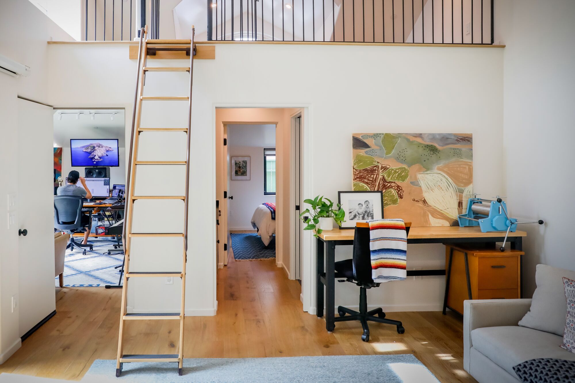 Une vue d'un escalier menant à un grenier, et une porte menant à un bureau avec un homme travaillant à côté du grenier