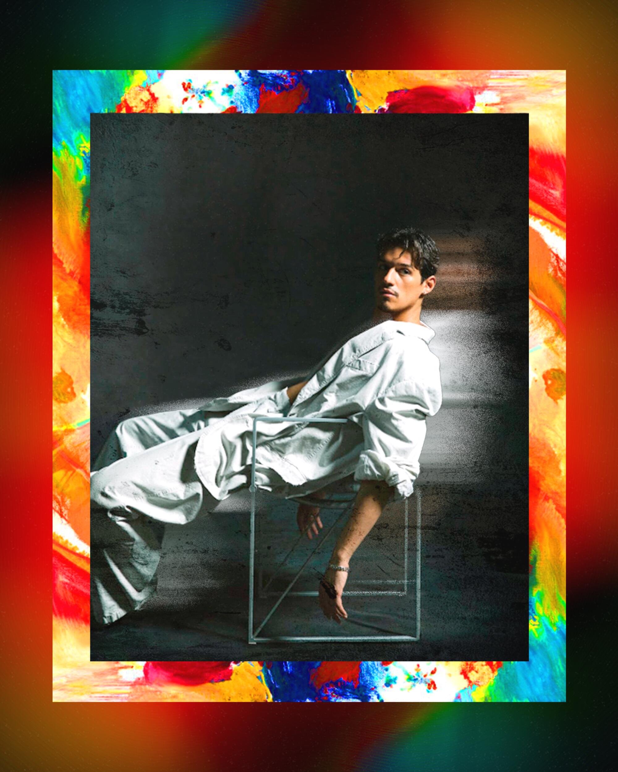 A photo illustration of Omar Apollo sitting in a chair, partly blurred as if he's moving, in a frame of multicolored paints