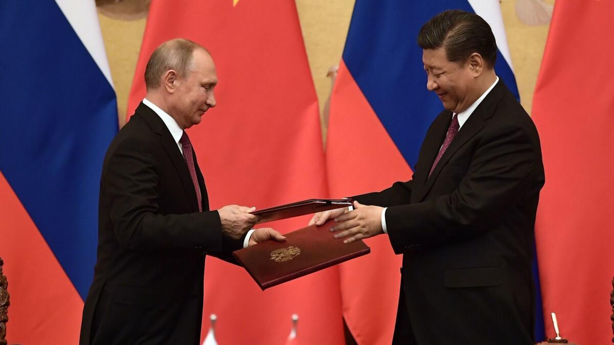 Russian President Vladimir Putin and Chinese President Xi Jinping exchange documents during a signing ceremony inside the Great Hall of the People in Beijing on June 8, 2018.