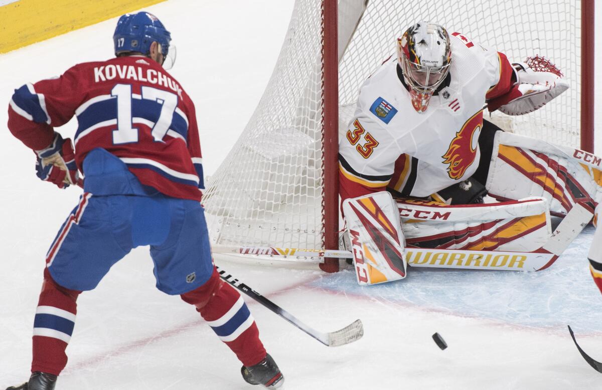 Canadiens left wing Ilya Kovalchuk and Flames goaltender David Rittich looking at the puck.