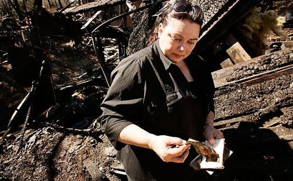 Anna Cox sorts through family photographs that she recovered from her burned home Tuesday in the Twin Lakes neighborhood of Chatsworth. More photos >>>