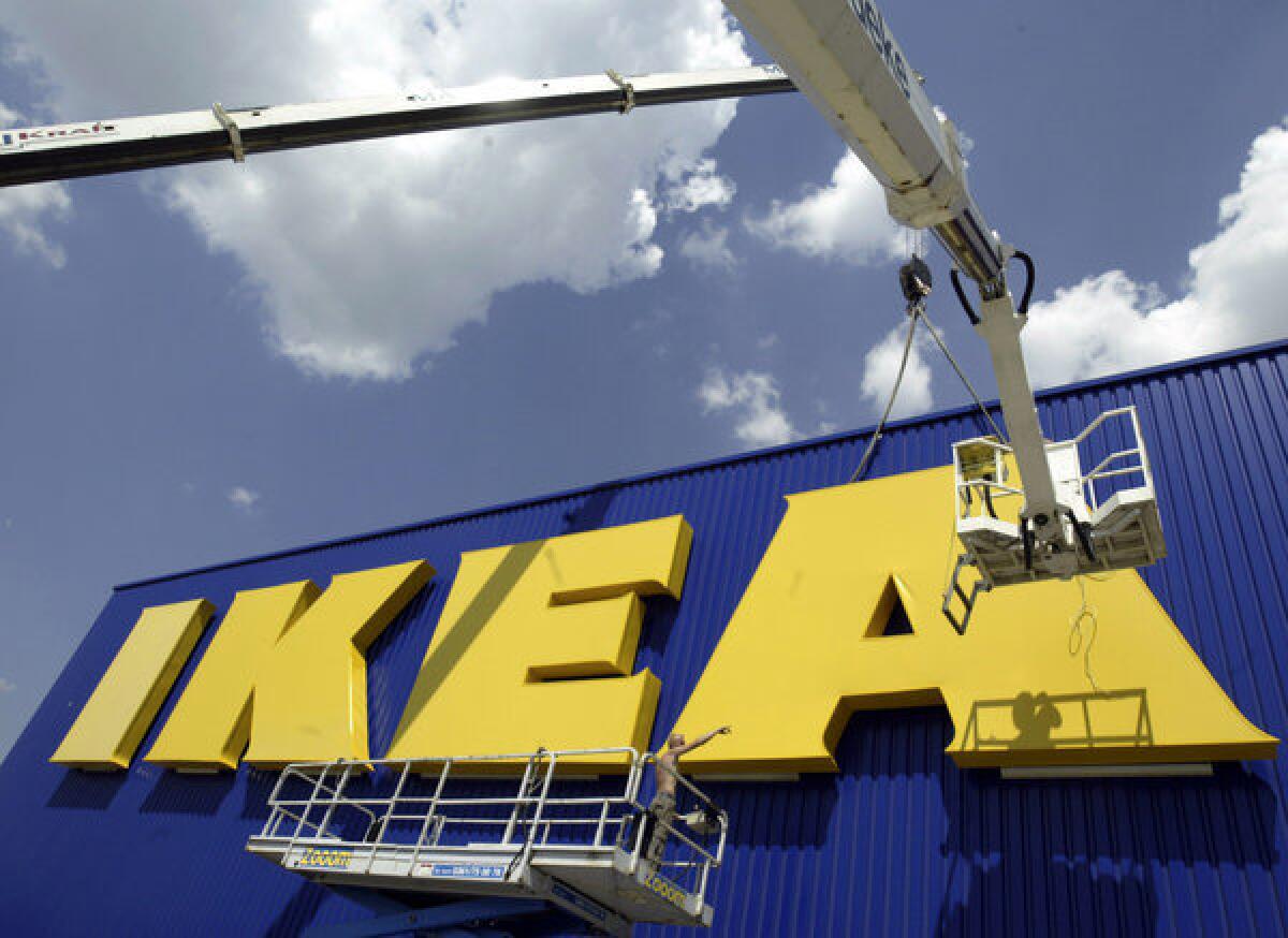 Workers affix the Ikea logo to a new store in eastern Germany. Ikea published a report showing that the company benefited from forced labor in communist East Germany.