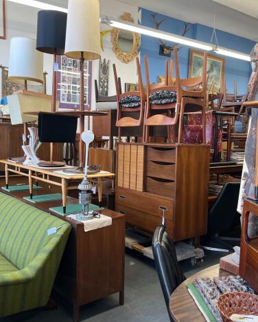 A green sofa and stacked chairs among other furniture at Hernandez Furniture.