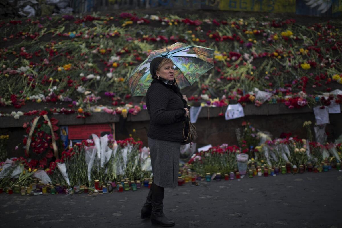A woman looks at flowers left at a memorial for protesters killed in clashes with police at Kiev's Independence Square in Ukraine.