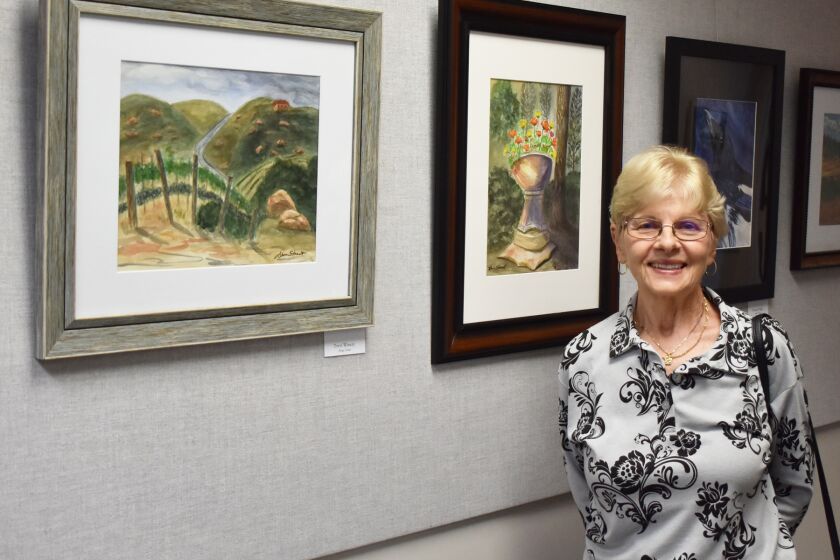 Mount Woodson resident Ahna Street with two of her paintings in the RB Library, “Trevi Winery” and “Planter in the Forest.”